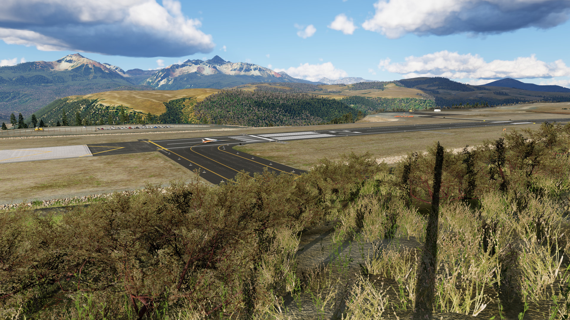 View of runway 9 from hill with bushes and 3d grass in the foreground at KTEX Telluride Regional Airport in X-Plane 12